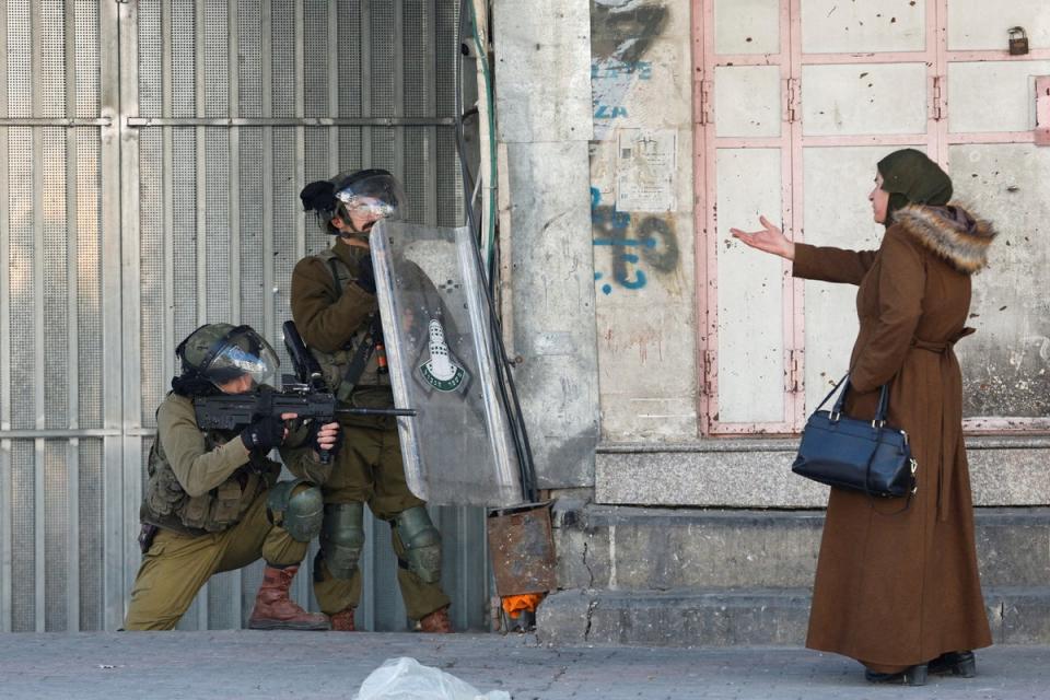 A Palestinian woman gestures in front of Israeli troops during a protest over the killing of three Palestinian gunmen by Israeli forces, in Hebron in the Israeli-occupied West Bank (Reuters)