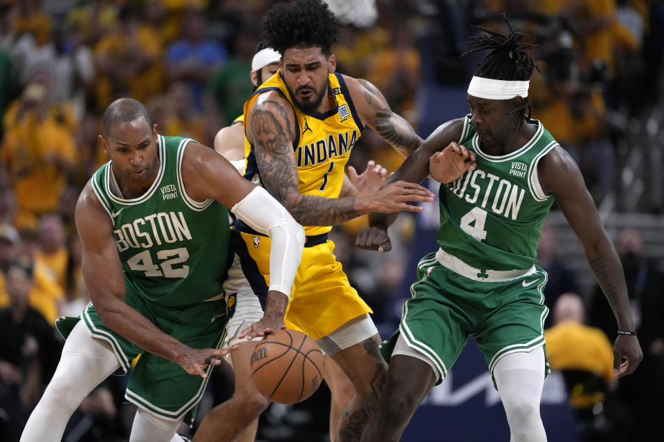 Indiana Pacers forward Obi Toppin, center, fights for a loose ball with Boston Celtics center Al Horford (42) and guard Jrue Holiday (4) during the second half of Game 4 of the NBA Eastern Conference basketball finals, Monday, May 27, 2024, in Indianapolis. (AP Photo/Michael Conroy)