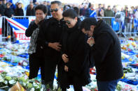 <p>Aiyawatt Srivaddhanaprabha lays a wreath in memory of his father with his mother Aimon (second right). Mike Egerton/PA Wire </p>