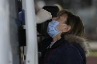 A member of the medical staff at the National Public Health Organisation (EODY) conducts a COVID-19 rapid test on a woman in Athens, Greece, Wednesday, Dec. 29, 2021. A government committee of medical experts hold an emergency meeting Wednesday to consider speeding up scheduled restrictions after the daily number of COVID-19 infections more than doubled in a day to set a new record. (AP Photo/Thanassis Stavrakis)