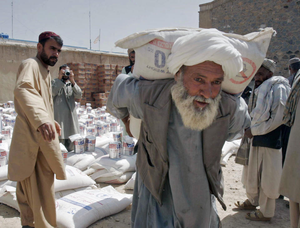 FILE - In this May 10, 2009 file photo, a man carries a sack of wheat distributed to poor displaced families, distributed by World Food Program with the cooperation of United Nations Assistance Mission in Afghanistan and the United States Agency for International Development, in Kandahar Afghanistan. After 20 years America is ending its “forever” war in Afghanistan. With a poverty rate of 54 per cent, which means the majority of Afghans are living on $1.90, the majority of Afghans hold out little hope for their future according to a 2018 Gallup poll. (AP Photo/Allauddin Khan, File)