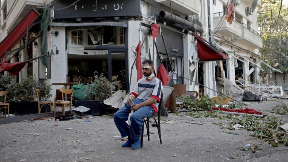 Un hombre se sienta frente a un restaurante destruido por la explosion el 5 de agosto de 2020