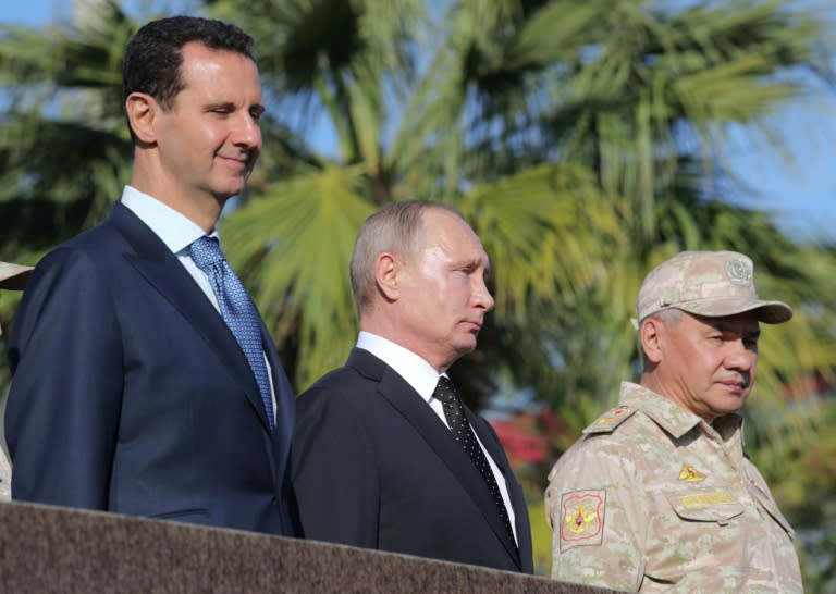 Putin, Assad and Russian Defence Minister Sergei Shoigu inspect a military parade during their visit to the Russian air base in Hmeimim in the northwestern Syrian province of Latakia