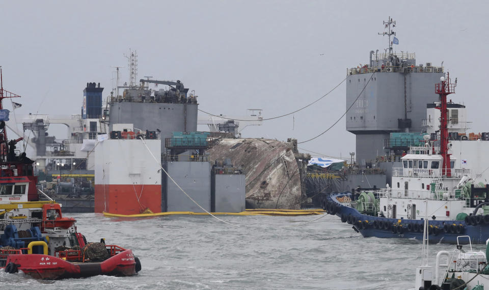 The sunken Sewol ferry is loaded onto a semi-submersible transport vessel during the salvage operation in waters off Jindo, South Korea, Saturday, March 25, 2017. Salvage crews towed the corroded 6,800-ton South Korean ferry toward a transport vessel on Friday after it was successfully raised from waters off the country's southwest coast. The massive attempt to bring the ferry back to shore, nearly three years after it sank, killing 304 people, is being closely watched by a nation that still vividly remembers the horrific accident. (Lee Jin-wook/Yonhap via AP)