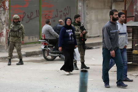 People walk as Turkish soldiers stand guard in the center of Afrin, Syria March 24, 2018. REUTERS/Khalil Ashawi