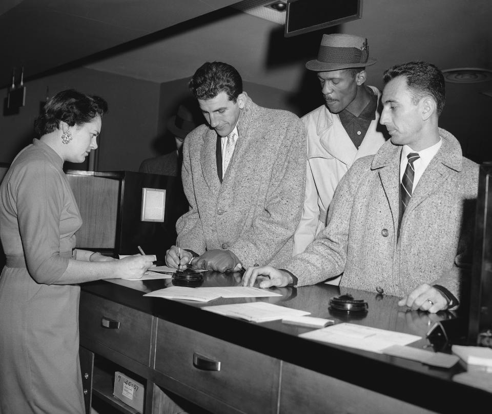 FILE - In this Jan. 20, 1958, file photo, three members of the Eastern Team in the NBA All Star game check in at a hotel in St. Louis, Mo., after they arrived for the game. They are, from left, Dolph Schayes of Syracuse, and Bill Russell and Bob Cousy, both of the Boston team. (AP Photo/File)