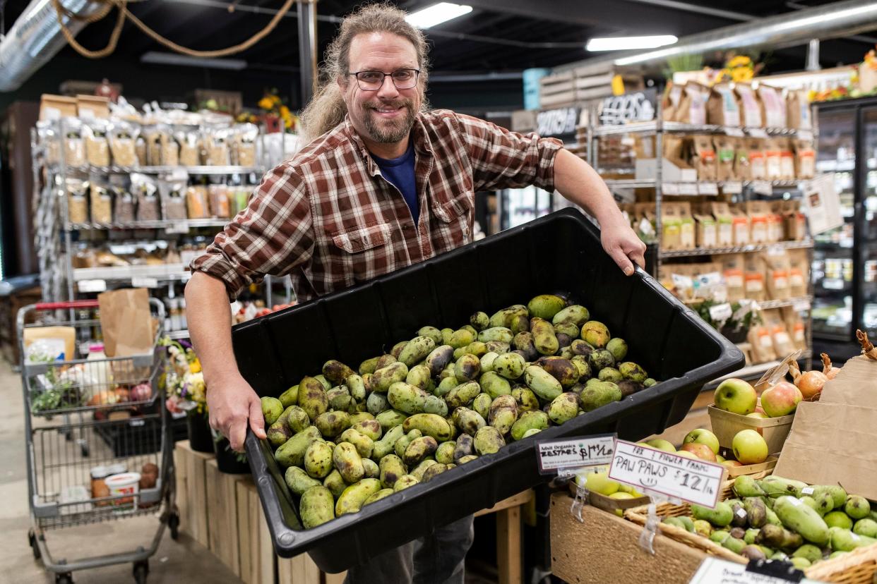 Store manager Brian Barch shows the pawpaws for sale at Argus Farm Stop in Ann Arbor on Thursday, Oct. 5, 2023.