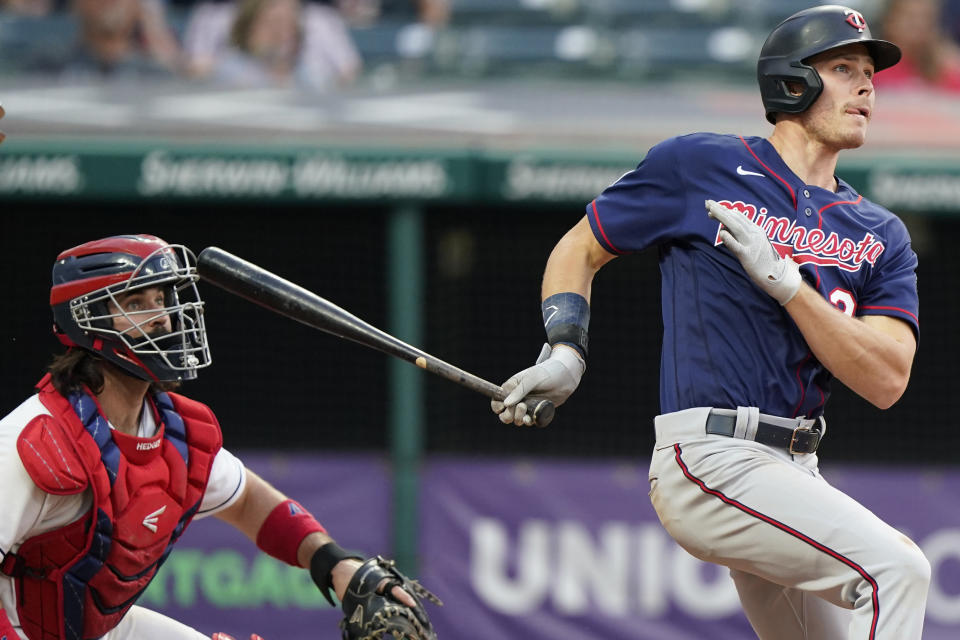 Minnesota Twins' Max Kepler, right, watches his two-run double in the fourth inning of a baseball game against the Cleveland Indians, Friday, May 21, 2021, in Cleveland. Indians catcher Austin Hedges, left, also watches the hit. (AP Photo/Tony Dejak)