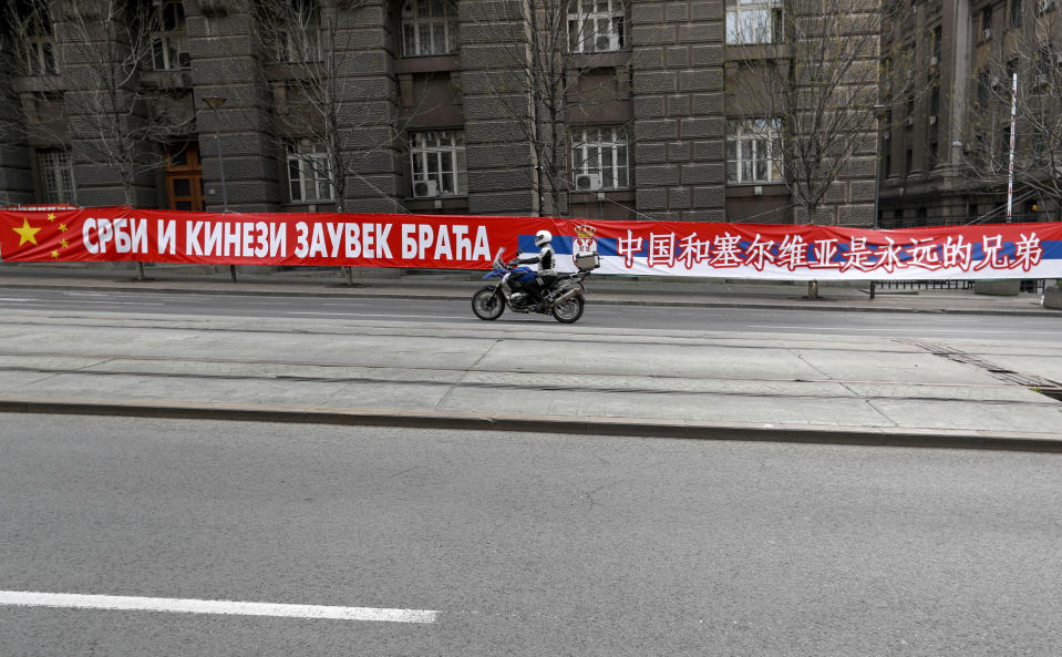 FILE - A motorcyclist rides past a billboard showing Serbian and Chinese flags that read: "Serbs and Chinese brothers forever" placed on a street prior to a curfew set up to help prevent the spread of the new coronavirus in Belgrade, Serbia, Monday, April 13, 2020. Chinese President Xi Jinping will visit France, Serbia and Hungary this week as Beijing appears to seek a larger role in the conflict between Russia and Ukraine that has upended global political and economic security. (AP Photo/Darko Vojinovic, File)