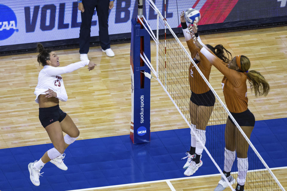 Wisconsin's Molly Haggerty (23) scores a point against Texas' Jhenna Gabriel (2) and Asjia O'Neal (7) during the first set of a semifinal in the NCAA women's volleyball championships Thursday, April 22, 2021, in Omaha, Neb. (AP Photo/John Peterson)
