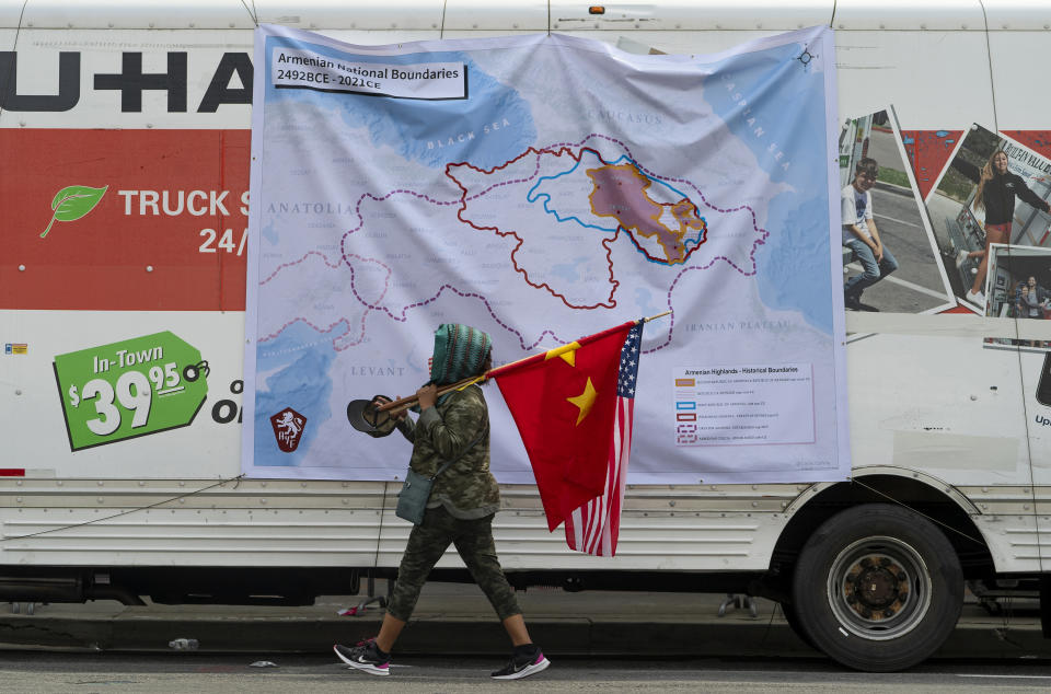 A protestor walks past a map hanging from a rental company at rally protesting against the Armenian genocide in Beverly Hills, Calif., Saturday, April 24, 2021. The systematic killing and deportation of more than a million Armenians by Ottoman Empire forces in the early 20th century was "genocide," the United States formally declared on Saturday, as President Joe Biden used that precise word after the White House had avoided it for decades for fear of alienating ally Turkey. (AP Photo/Damian Dovarganes)