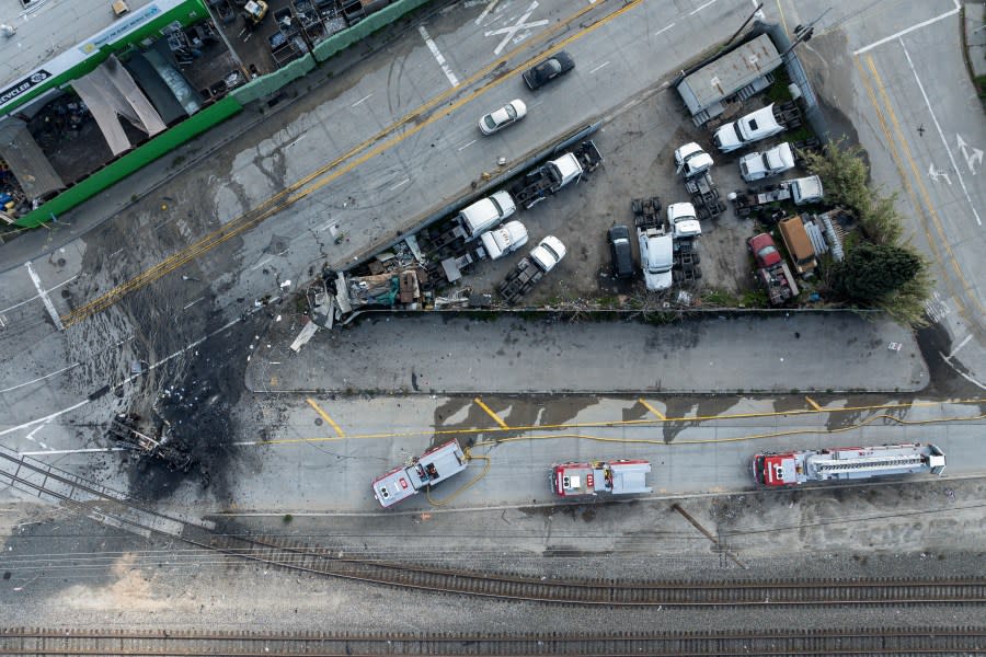 The tractor portion of a big rig, at left, is shown in an aerial view on Thursday, Feb. 15, 2024, in the Wilmington section of Los Angeles. Several Los Angeles firefighters were injured, two critically, when an explosion occurred as they responded to a truck with pressurized cylinders that were on fire early Thursday, authorities said. (AP Photo/William Liang)