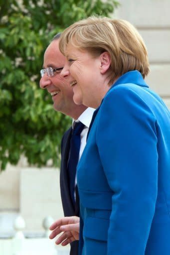 France's President Francois Hollande (L) accompagnies Germany's Chancellor Angela Merkel upon her arrival for a working dinner at the Elysee presidential palace in Paris