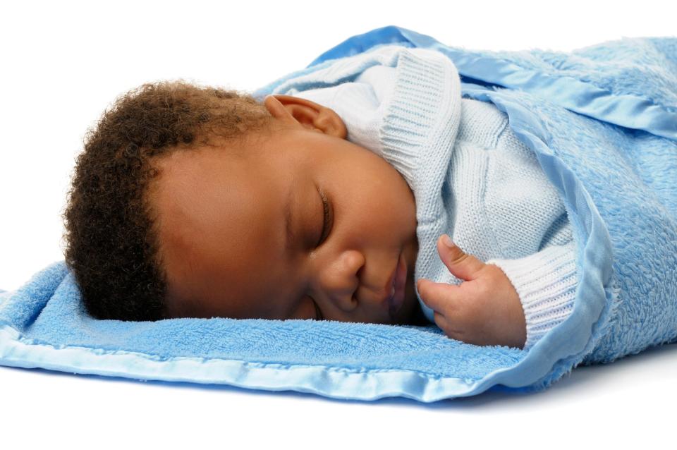 A newborn baby boy sleeps while wrapped in a blanket. Several companies have pulled sales of weighted baby blankets over safety concerns.