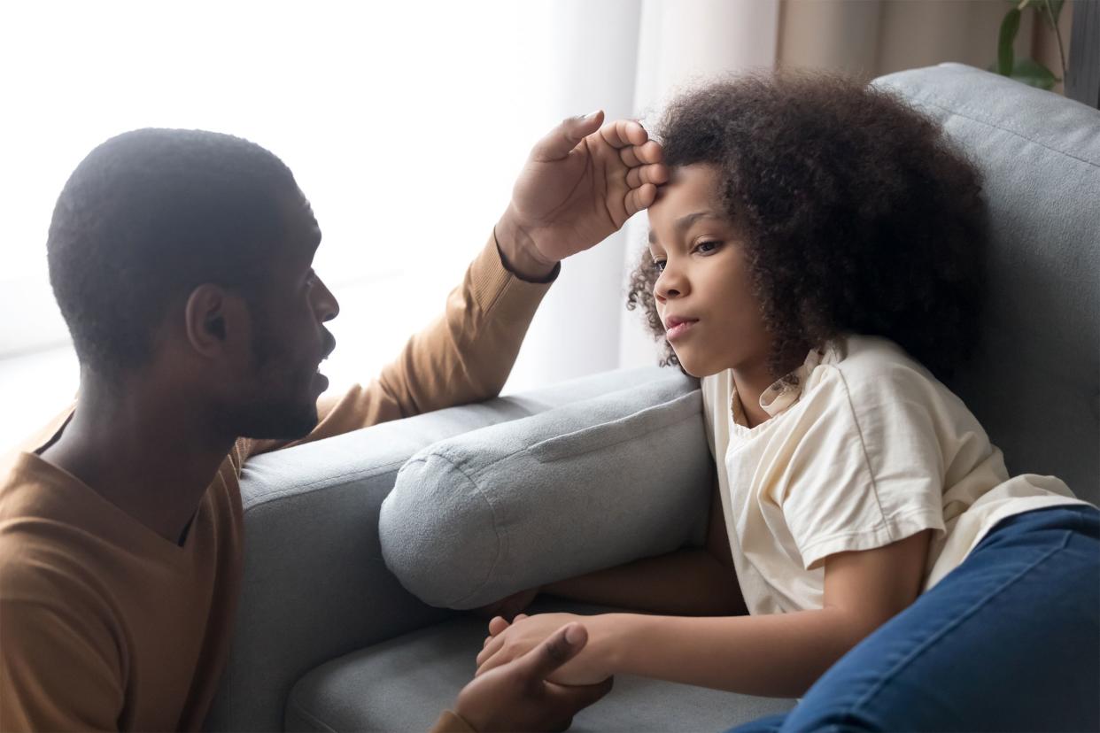 Father touching his daughter's forehead to check for temperature