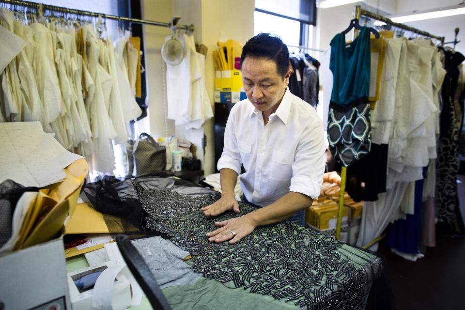 In this Aug 20, 2013 photo, Creative Director Il Park handles fabric in the workspace of fashion designer Carmen Marc Valvo's New York studio. Valvo will show his Spring 2014 show on Sept. 6 at Lincoln Center in New York. (AP Photo/John Minchillo)