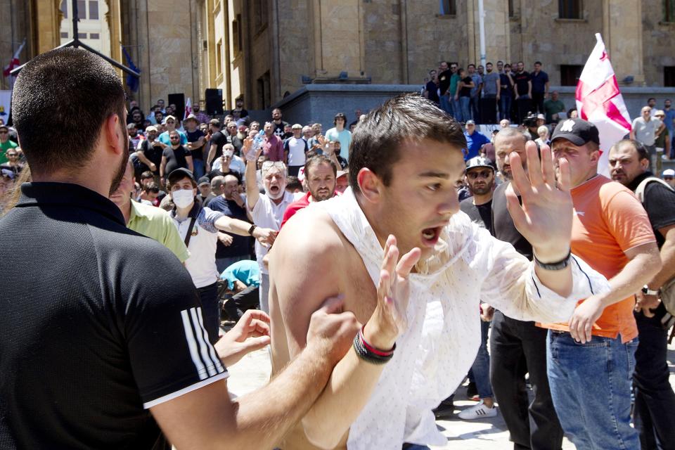 Opponents of the march push a man as they block off the capital's main avenue to an LGBT march in Tbilisi, Georgia, Monday, July 5, 2021. A protest against a planned LGBT march in the Georgian capital turned violent on Monday as demonstrators attacked journalists. Organizers of the Tbilisi March For Dignity that was to take place in the evening cancelled the event, saying authorities had not provided adequate security guarantees. (AP Photo/Shakh Aivazov)