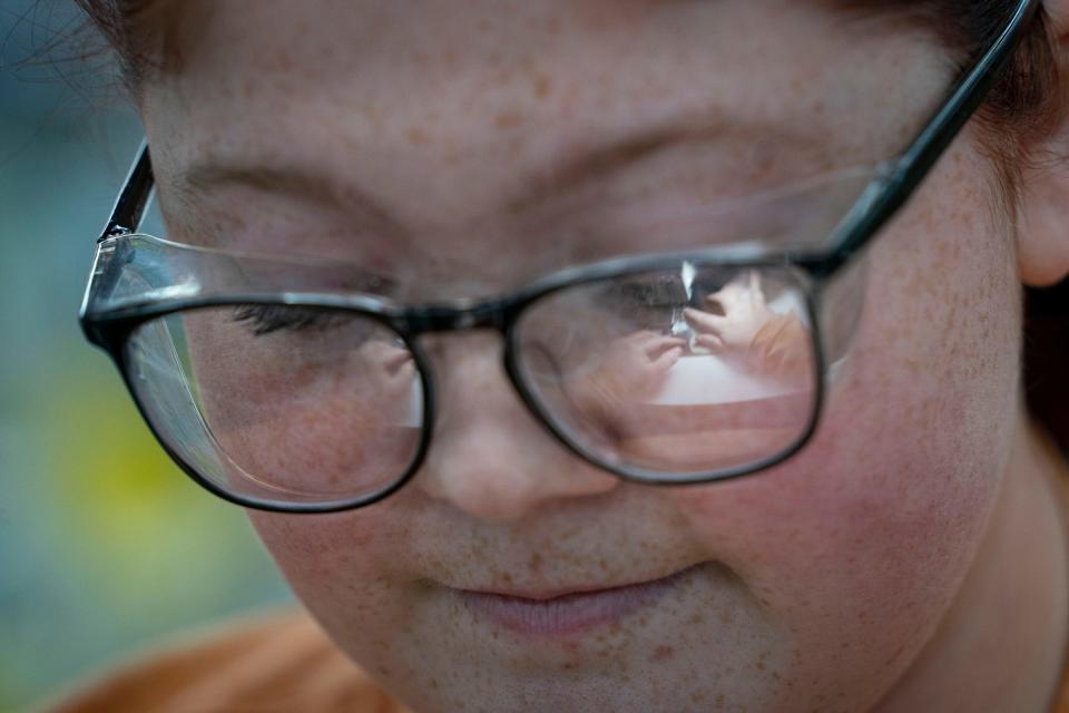 The hands of Katelynn Smith, 23, of Ironwood, can be seen reflected in her glasses as she sews the label into the Stormy Kromer hat in the Jacquart Fabric Products, home of Stormy Kromer, manufacturing facility in Ironwood on Thursday, Jan. 4, 2024.