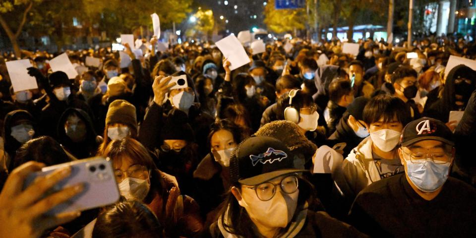 Protesters march along a street during a rally for the victims of a deadly fire as well as a protest against China's harsh Covid-19 restrictions in Beijing on November 28, 2022