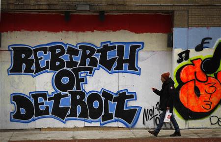 A man walks past graffiti in Detroit, Michigan, December 3, 2013. REUTERS/Joshua Lott