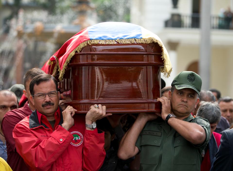 CORRECTS YEAR CHAVEZ WAS ELECTED PRESIDENT - Army mates of former Venezuelan Intelligence Chief Eliezer Otaiza carry his body outside the National Assembly during a funeral procession in Caracas, Venezuela, Wednesday, April 30, 2014. Otaiza's body was dumped on the edge of Caracas Saturday after his vehicle was intercepted by a group of armed men. No motive has been established for the crime. As a young army officer, he backed Hugo Chavez's failed 1992 coup attempt and was responsible for his personal security when he was elected president in 1998. The man at left is Carlos Alcala Cordones, former army commander and current Mayor of La Guaira. (AP Photo/Fernando Llano)