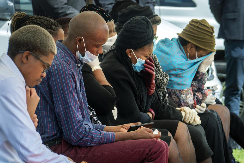 Family and friends mourn Benedict Somi Vilakasi at his burial ceremony at the Nasrec Memorial Park outside Johannesburg Thursday, April 16, 2020. Vilakasi, a Soweto coffee shop manager, died of Covid-19 infection in a Johannesburg hospital Sunday April 12 2020. South Africa is under a strict five-week lockdown in a effort to fight the Coronavirus pandemic.(AP Photo/Jerome Delay)