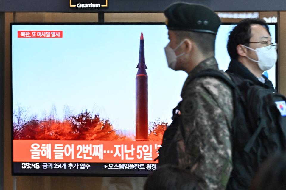 People walk past a television screen showing a news broadcast with file footage of a North Korean missile test, at a railway station in Seoul on January 11, 2022, after North Korea fired a 