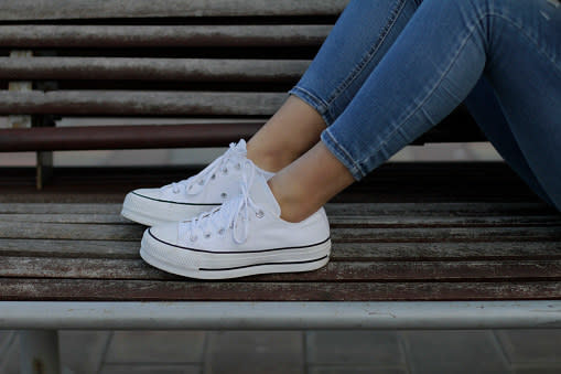 A model wearing white Converse shoes.