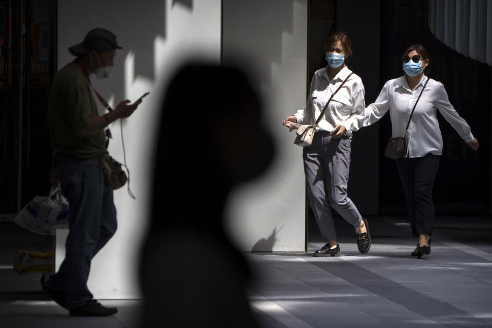People wearing face masks walk through a shopping and office complex in Beijing, Wednesday, Aug. 24, 2022. China is easing its tight restrictions on visas after it largely suspended issuing them to students and others more than two years ago at the start of the COVID-19 pandemic. (AP Photo/Mark Schiefelbein)