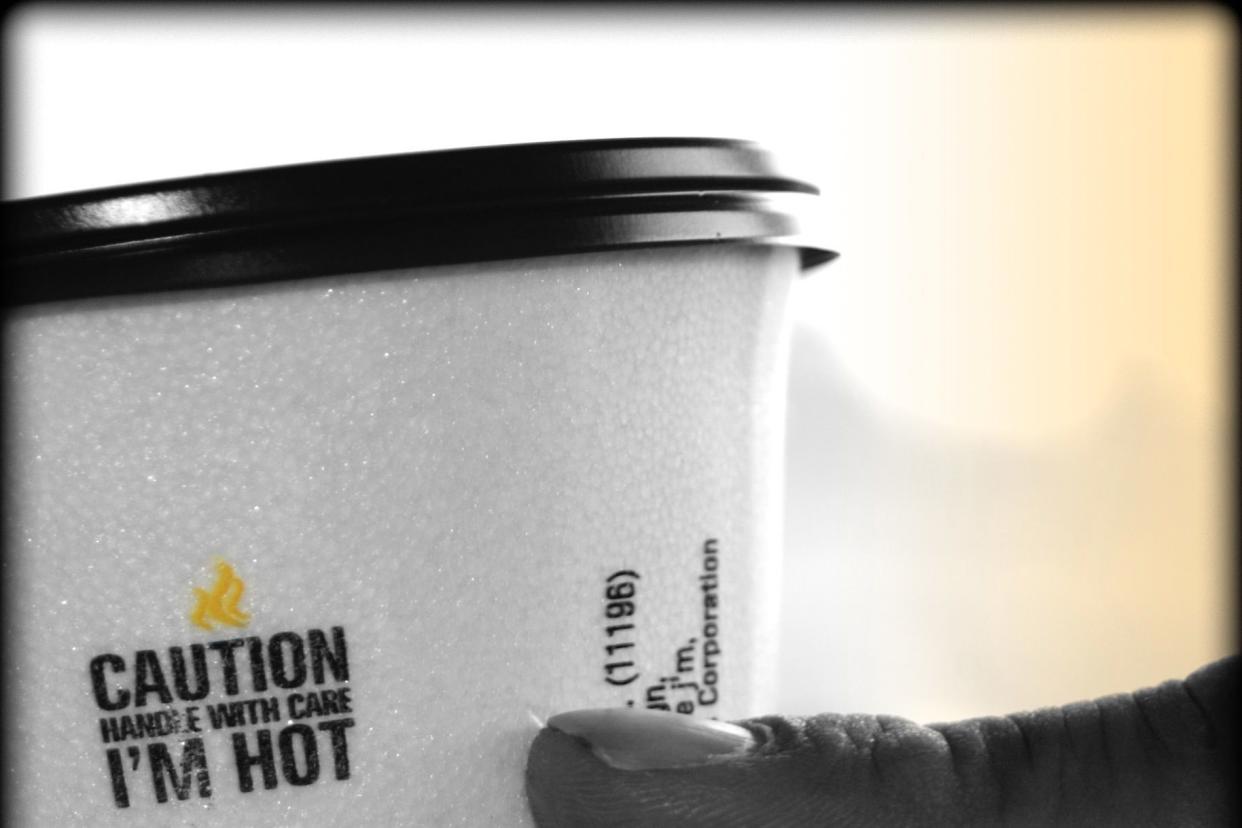 Man holding coffee cup marked 'Caution Handle with Care I'm Hot.'