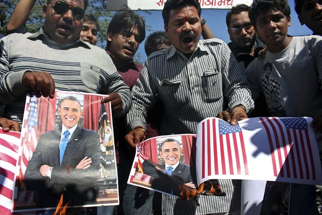 Activists of Sanskriti Bachao Manch, or save culture forum, burn posters of U.S. President Barack Obama and U.S. flags during a demonstration to protest against the alleged mistreatment of New York based Indian diplomat Devyani Khobragade, in Bhopal, India, Wednesday, Dec. 18, 2013. The Indian diplomat said she faced repeated "handcuffing, stripping and cavity searches" following her arrest in New York City on visa fraud charges in a case that has infuriated the government in New Delhi. (AP Photo/Rajeev Gupta)