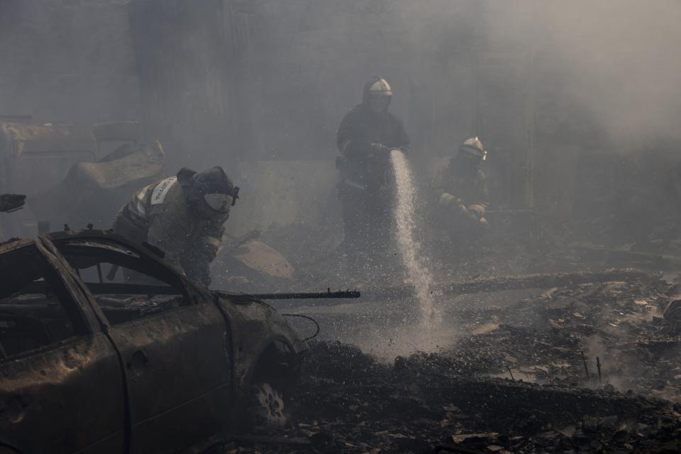 Donetsk People Republic Emergency Situations Ministry employees at the scene of burned vehicles after the shelling in the Leninsky district of Donetsk, on the territory which is under the Government of the Donetsk People's Republic control, eastern Ukraine, Monday, June 6, 2022. (AP Photo/Alexei Alexandrov)