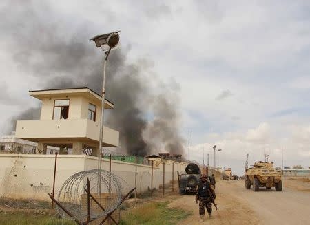 An Afghan security walks as smoke billows from a building after a Taliban attack in Gereshk district of Helmand province, Afghanistan March 9, 2016. REUTERS/Abdul Malik