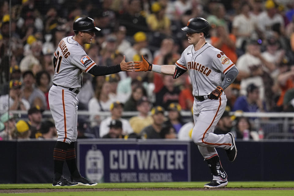San Francisco Giants' Mike Yastrzemski, right, celebrates with third base coach Mark Hallberg after hitting a home run during the fifth inning of a baseball game against the San Diego Padres, Thursday, Aug. 31, 2023, in San Diego. (AP Photo/Gregory Bull)
