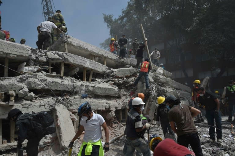 Rescuers and volunteers search for survivors amid the rubble and debris of a multistory building flattened by the 7.1-magnitude quake