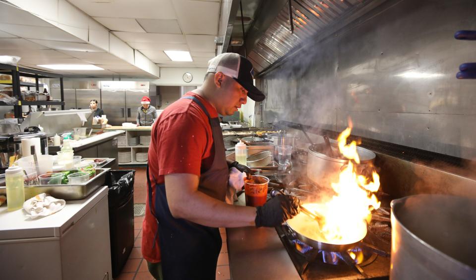 Chef and owner Fidelio Rita kicks up the heat as he prepares Pescado A La Veracruzana at the newly opened Neno's restaurant at 642 Monroe Ave. in Rochester Tuesday, Dec. 24, 2019.  The dish features pan seared red snapper, served with white rice, capers, olives, tomatoes sauce, fresh jalape–os, red onions and fresh cilantro. 