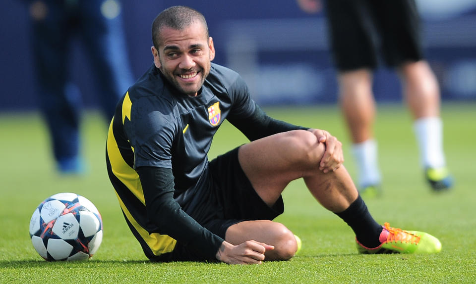 FC Barcelona's Daniel Alves, from Brazil, smiles as he holds his knee during a training session at the Sports Center FC Barcelona Joan Gamper in San Joan Despi, Spain, Tuesday, March 11, 2014. FC Barcelona will play against Manchester City in a group H Champions League on Wednesday March 12. (AP Photo/Manu Fernandez)