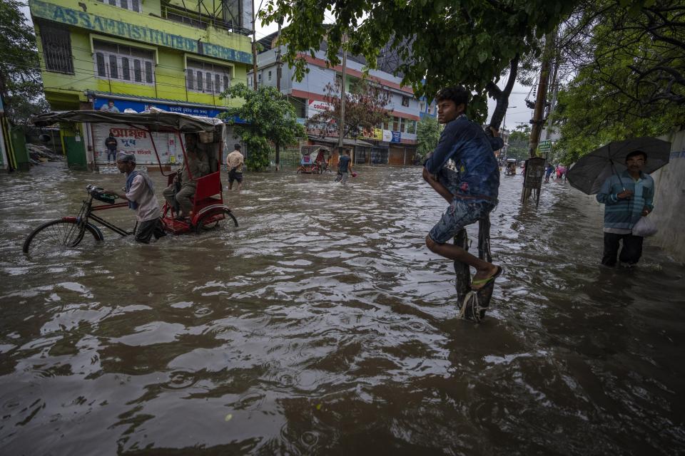 People wade through a flooded road after heavy rains in Gauhati, Assam state, India, on June 14, 2022. (AP Photo/Anupam Nath)