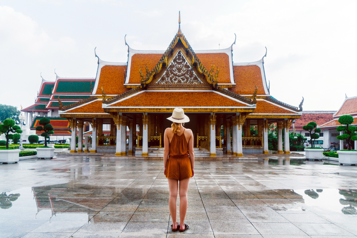 Woman in shorts and tank top standing outside of a temple