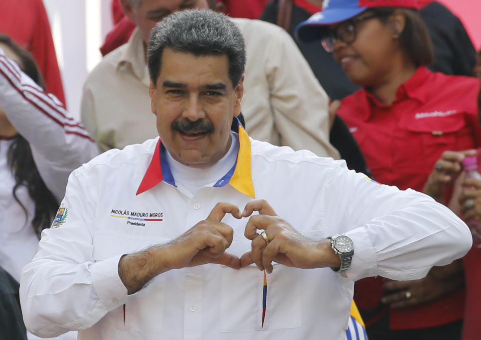 In this May 20, 2109 photo, Venezuela's President Nicolas Maduro flashes a hand-heart symbol to supporters outside Miraflores presidential palace in Caracas, Venezuela. Maduro said Thursday, May 23, 2019, that he iss inviting China's Huawei to help set up a 4G network in Venezuela, prompting opposition leader Juan Guaidó to accuse him of having an "absolute disconnection with reality." (AP Photo/Ariana Cubillos)