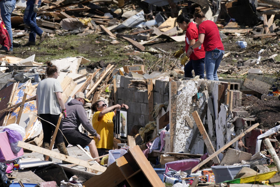 Local residents clean up debris from a tornado damaged home, Wednesday, May 22, 2024, in Greenfield, Iowa. (AP Photo/Charlie Neibergall)