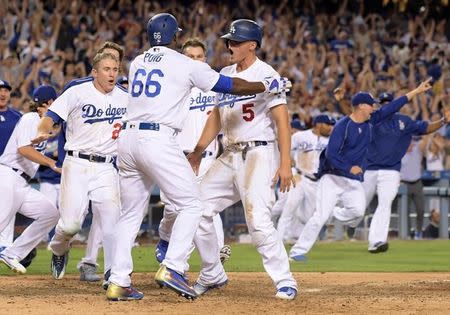 Sep 19, 2016; Los Angeles, CA, USA; Los Angeles Dodgers shortstop Corey Seager (5) celebrates with right fielder Yasiel Puig (66) after scoring in the ninth inning on a walk-off double by first baseman Adrian Gonzalez (not pictured) during a 2-1 victory over the San Francisco Giants in a MLB game at Dodger Stadium. Mandatory Credit: Kirby Lee-USA TODAY Sports