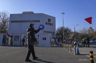 A man flies kite near residents get their routine COVID-19 throat swabs at a coronavirus testing site in Beijing, Sunday, Dec. 4, 2022. China on Sunday reported two additional deaths from COVID-19 as some cities move cautiously to ease anti-pandemic restrictions amid increasingly vocal public frustration over the measures. (AP Photo/Andy Wong)