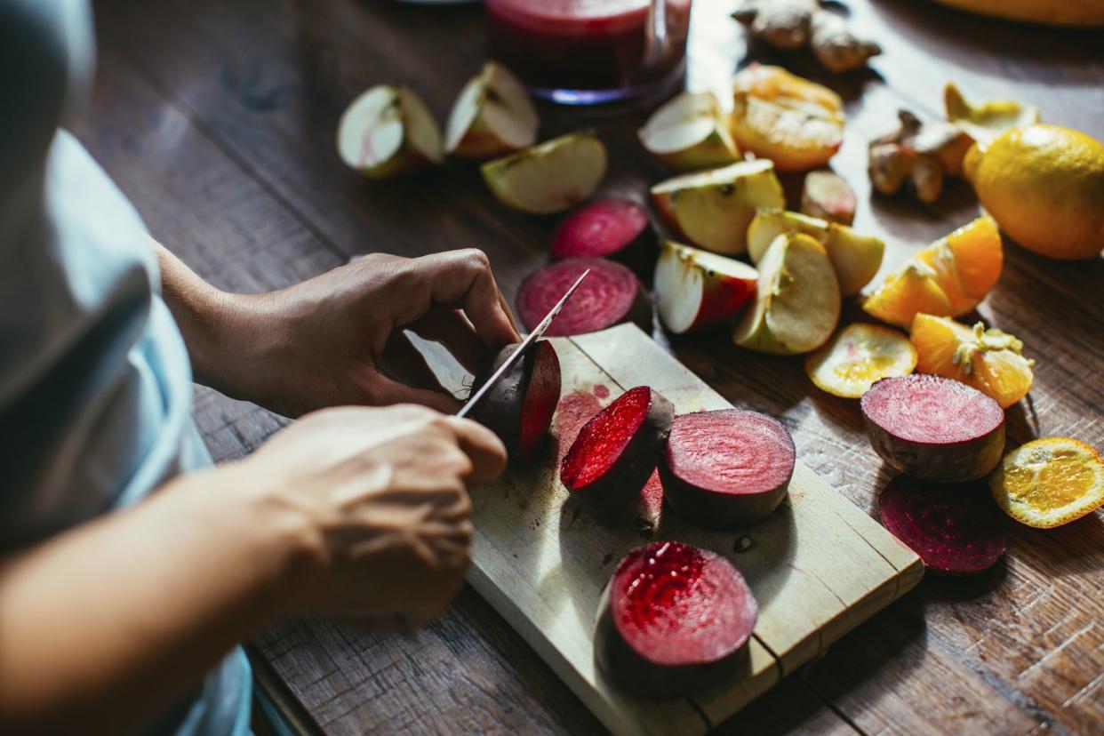 woman's hands chopping beetroot for squeezing juice