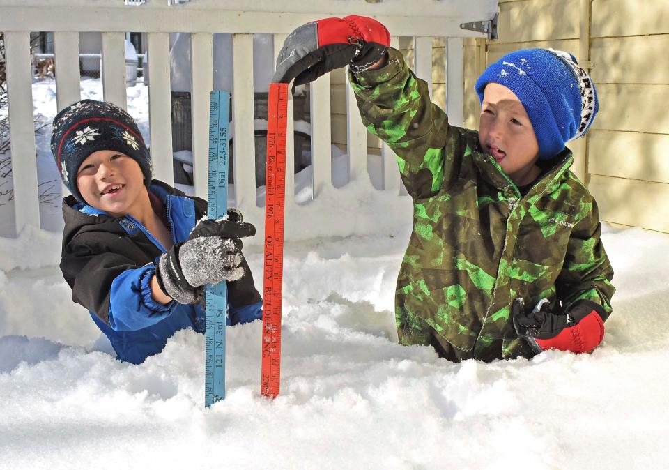 Two boys with yardsticks measure the snow depths near their home in north Bismarck, North Dakota, on Friday, Nov. 11, 2022.