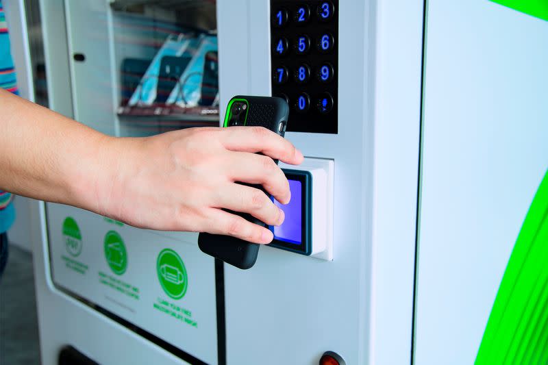 A smartphone is held next to a vending machine that dispenses masks made by Razer in Singapore