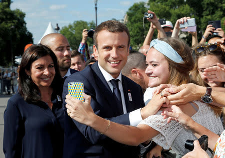 FILE PHOTO: French President Emmanuel Macron (C) poses for a selfie with Paris Mayor Anne Hidalgo (L) during a visit to a site on the Pont Alexandre III in Paris, France, June 24, 2017. REUTERS/Jean-Paul Pelissier/File Photo
