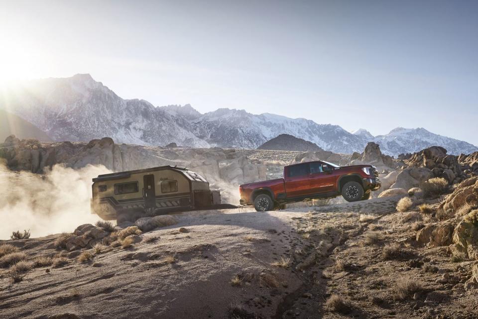 2024 gmc sierra 2500hd at4x towing a trailer through rocky mountain terrain