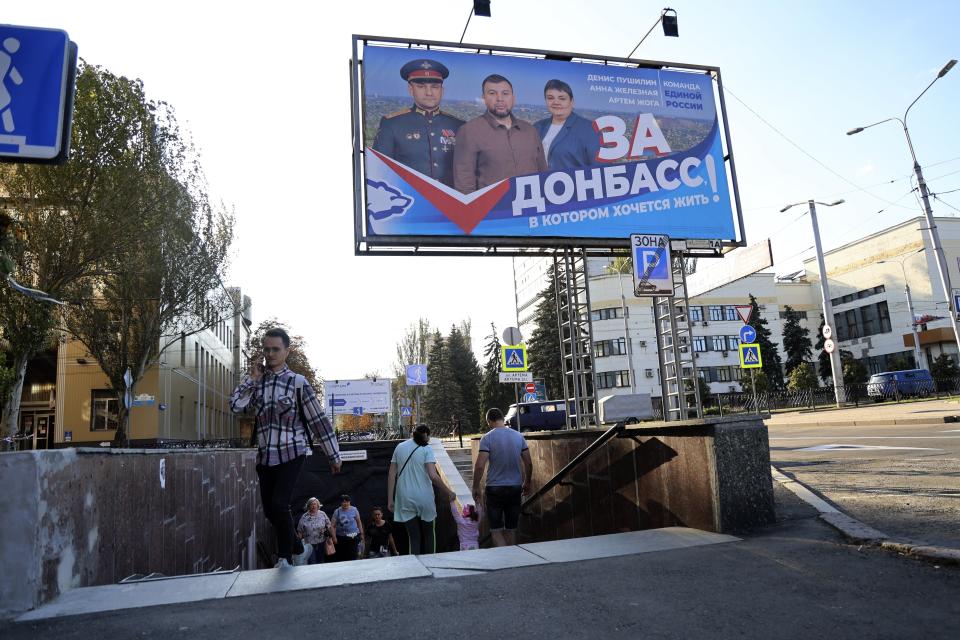 Varias personas utilizan un pasillo subterráneo próximo a un anuncio del partido Rusia Unida que dice: "¡Por el Donbás donde usted quiere vivir!", el jueves 7 de septiembre de 2023, antes de las elecciones locales en Donetsk, la capital de la región de Donetsk controlada por Rusia en el este de Ucrania. (AP Foto)