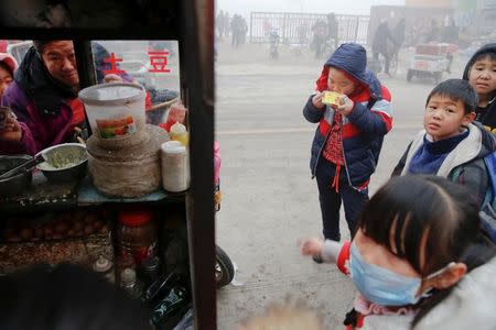 Children buy food outside their school as heavy smog blankets Shenfang in Hebei province, on an very polluted day December 20, 2016. REUTERS/Damir Sagolj